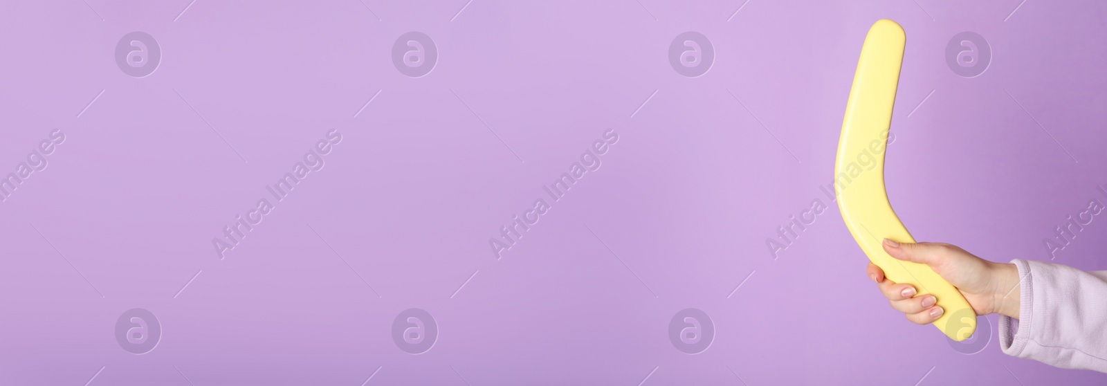 Photo of Woman holding boomerang on lilac background, closeup. Space for text