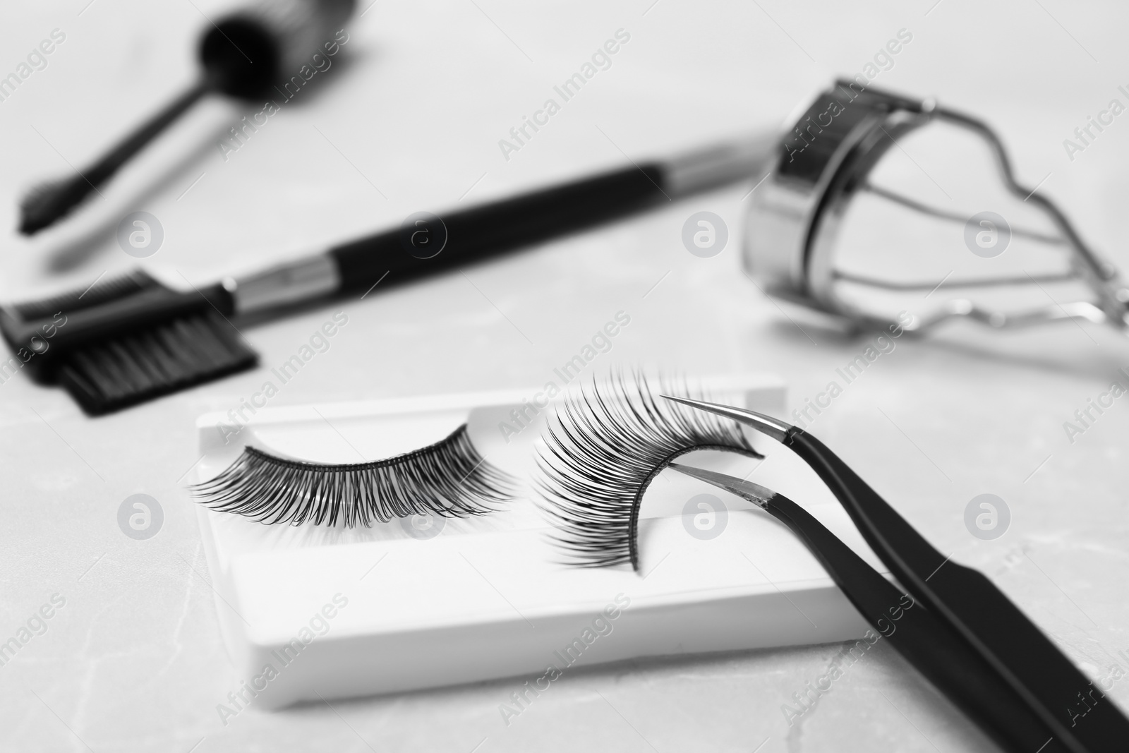 Photo of Tweezers and false eyelashes on table, closeup