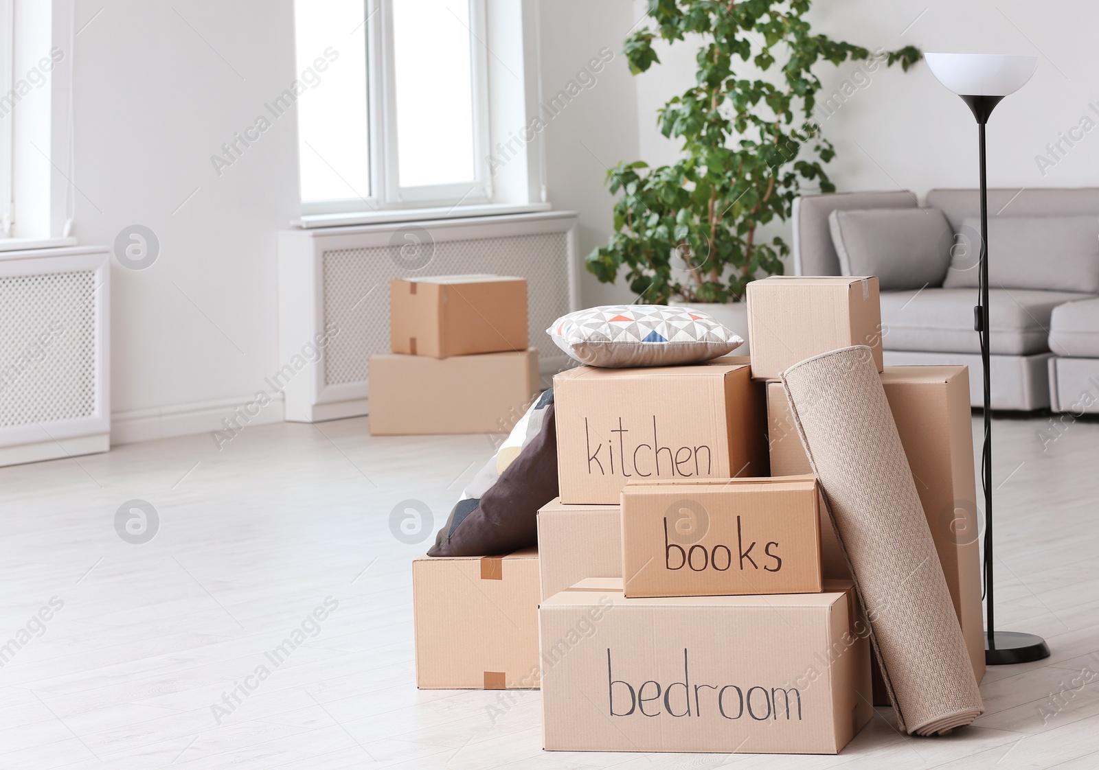 Photo of Pile of moving boxes and household stuff in living room