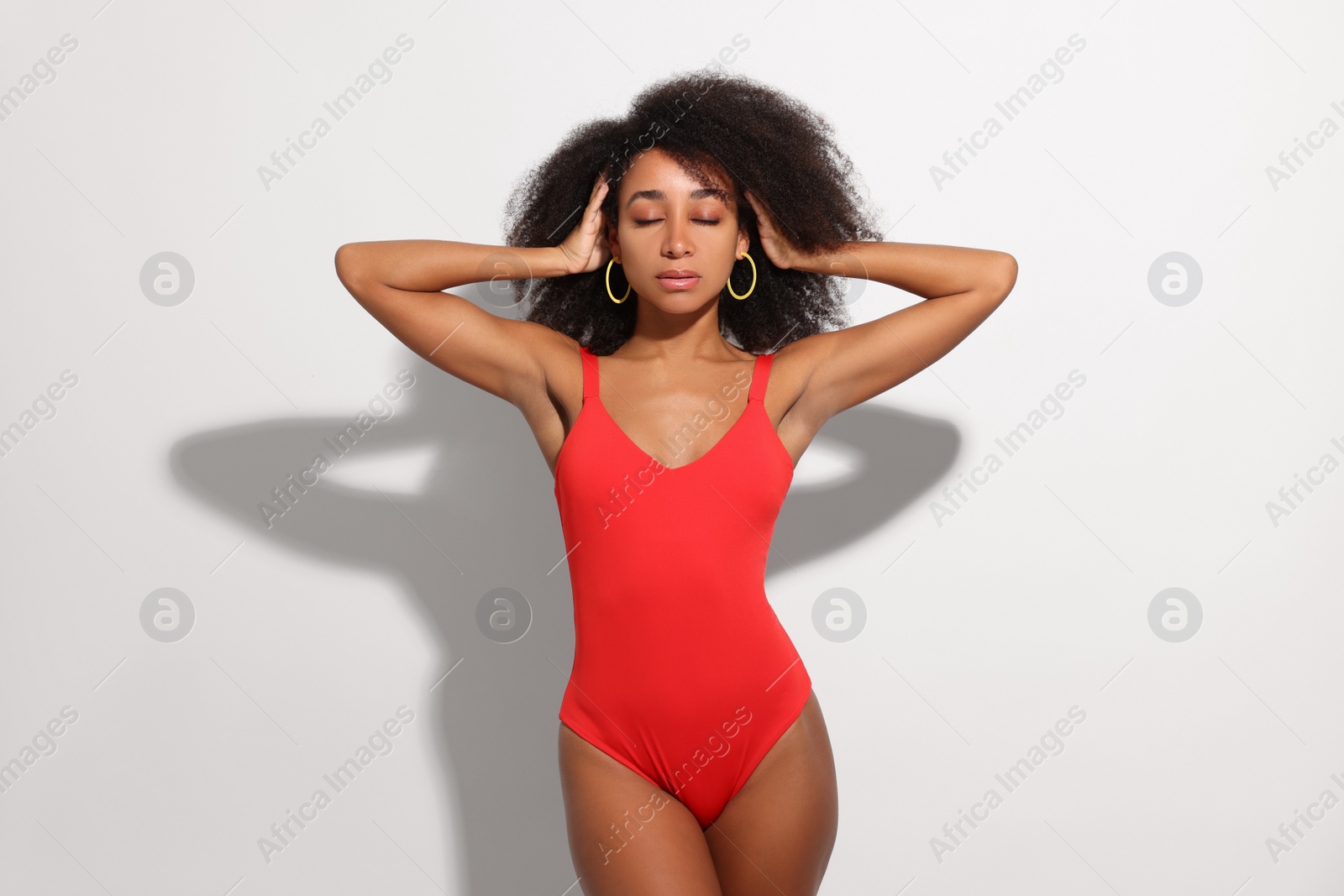 Photo of Beautiful woman in red one-piece summer swimsuit on white background