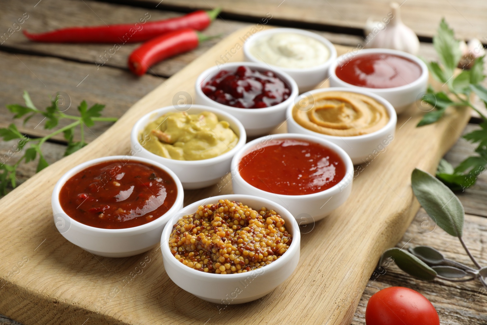 Photo of Different tasty sauces in bowls and ingredients on wooden table, closeup