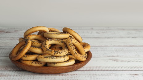 Photo of Plate with delicious ring shaped Sushki (dry bagels) on white wooden table. Space for text