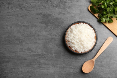 Photo of Boiled rice in bowl served on grey table, top view with space for text