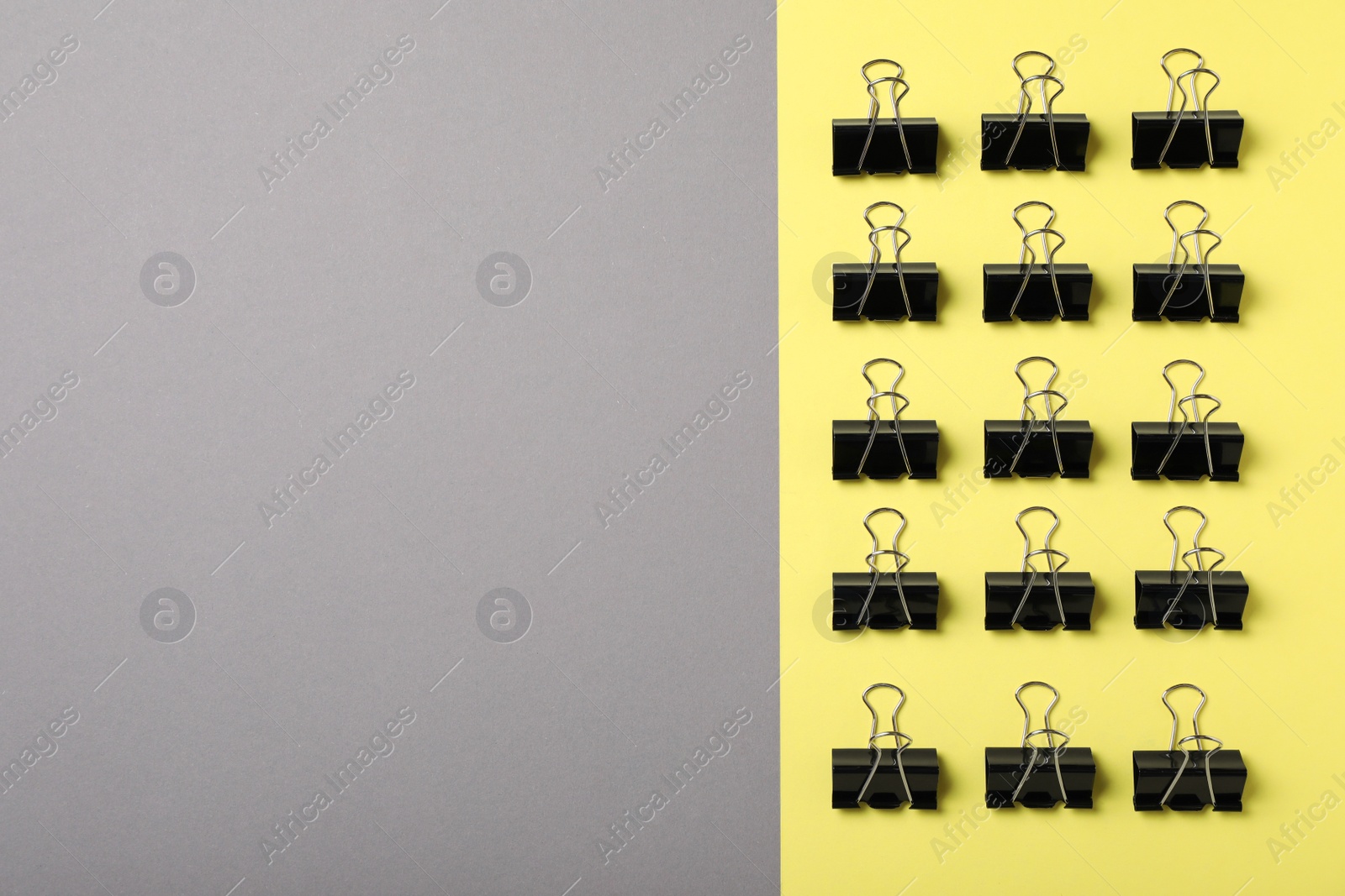 Photo of Black binder clips on color background, flat lay. Space for text