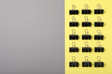 Photo of Black binder clips on color background, flat lay. Space for text