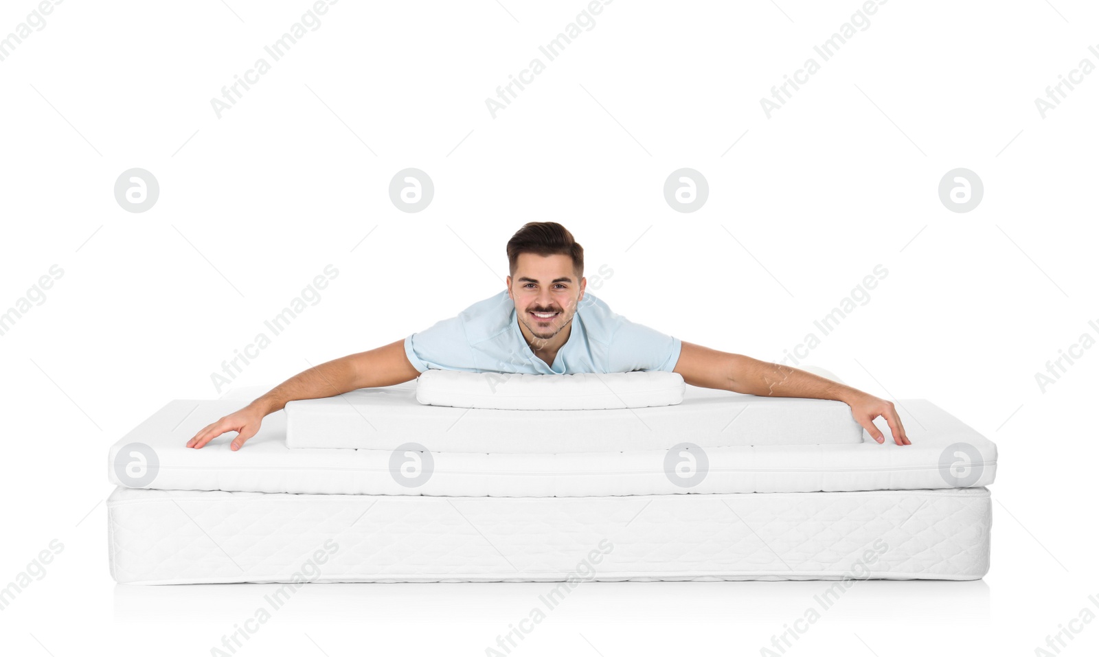 Photo of Young man lying on mattress pile against white background