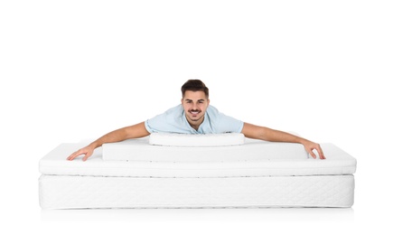 Young man lying on mattress pile against white background