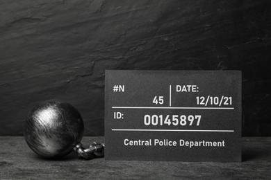 Photo of Metal ball with chain and mugshot letter board on grey table