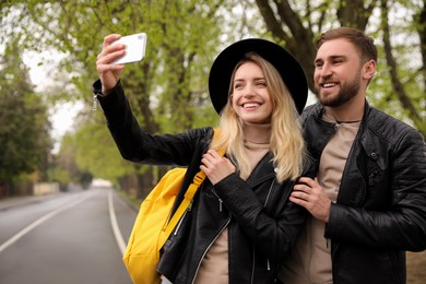 Lovely couple with smartphone taking selfie on spring day