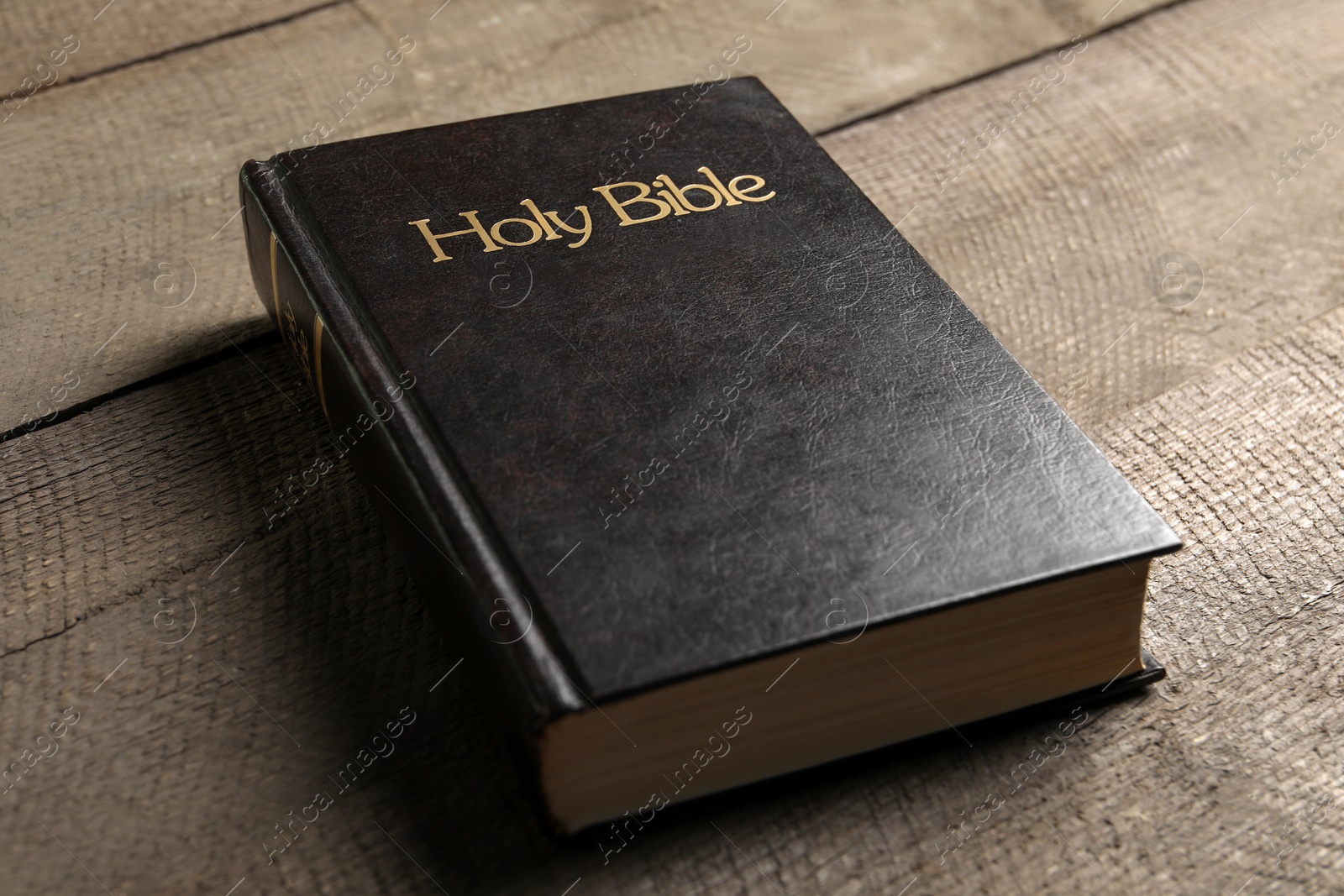 Photo of One hardcover Bible on wooden table, closeup