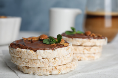 Photo of Puffed rice cakes with chocolate spread on white wooden table, closeup