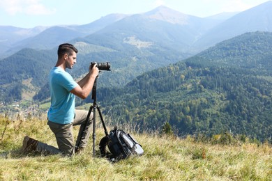 Photographer with backpack, camera and tripod surrounded by breathtakingly beautiful nature