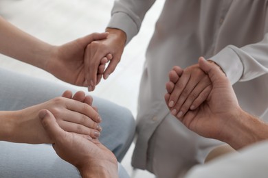 Photo of Group of religious people holding hands and praying together indoors, closeup