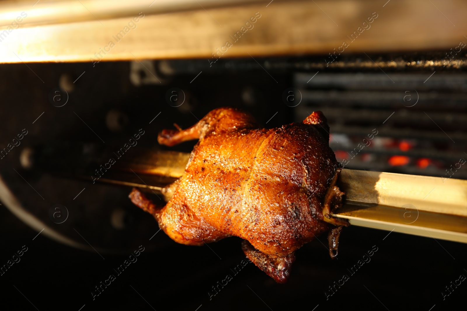 Photo of Grilling whole delicious duck in rotisserie machine, closeup