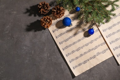 Composition with Christmas balls and music sheets on grey background, top view. Space for text