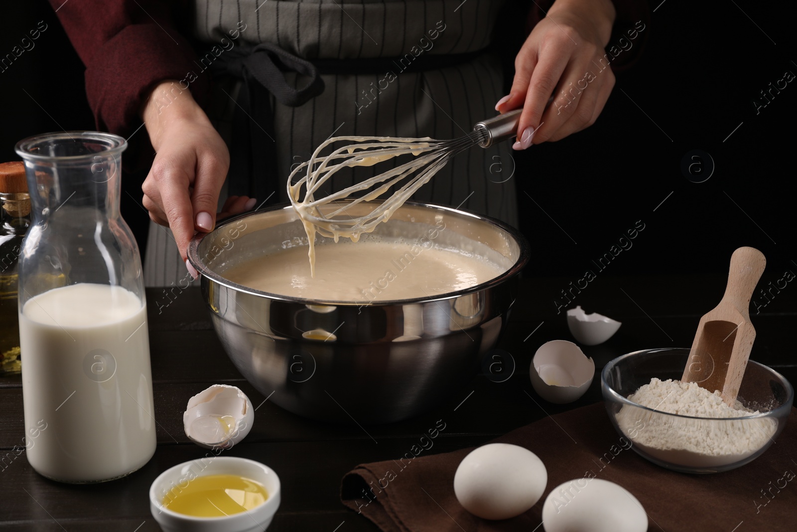 Photo of Woman making dough with whisk in bowl at table, closeup