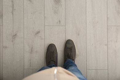 Photo of Person in brown shoes standing on wooden floor, top view. Space for text