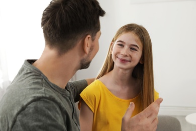 Photo of Father talking with his teenager daughter at home