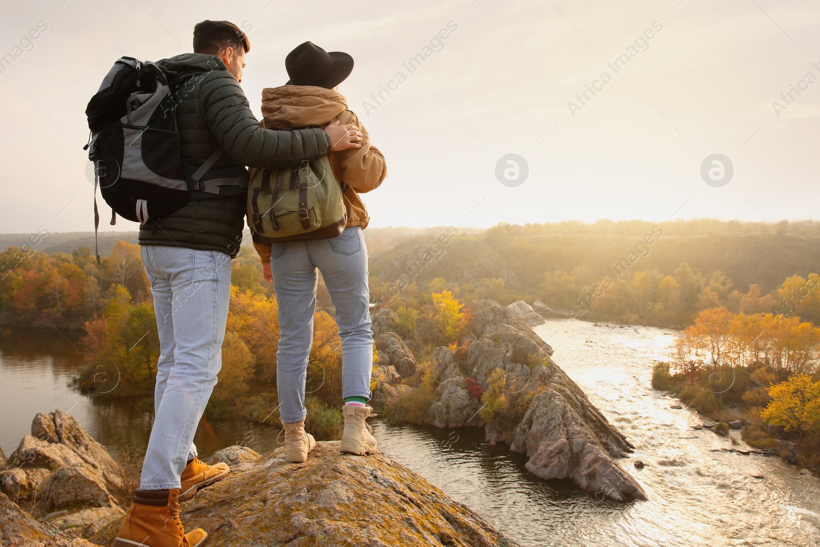 Photo of Couple of hikers with backpacks near mountain river, back view