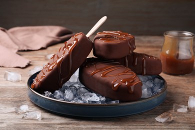 Photo of Delicious glazed ice cream bars and ice cubes on wooden table