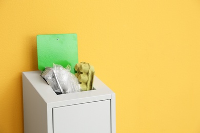 Photo of Overfilled trash bin on color background, space for text. Recycling concept