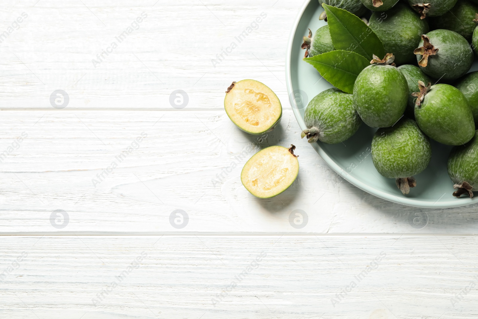 Photo of Flat lay composition with fresh green feijoa fruits on white wooden table, space for text