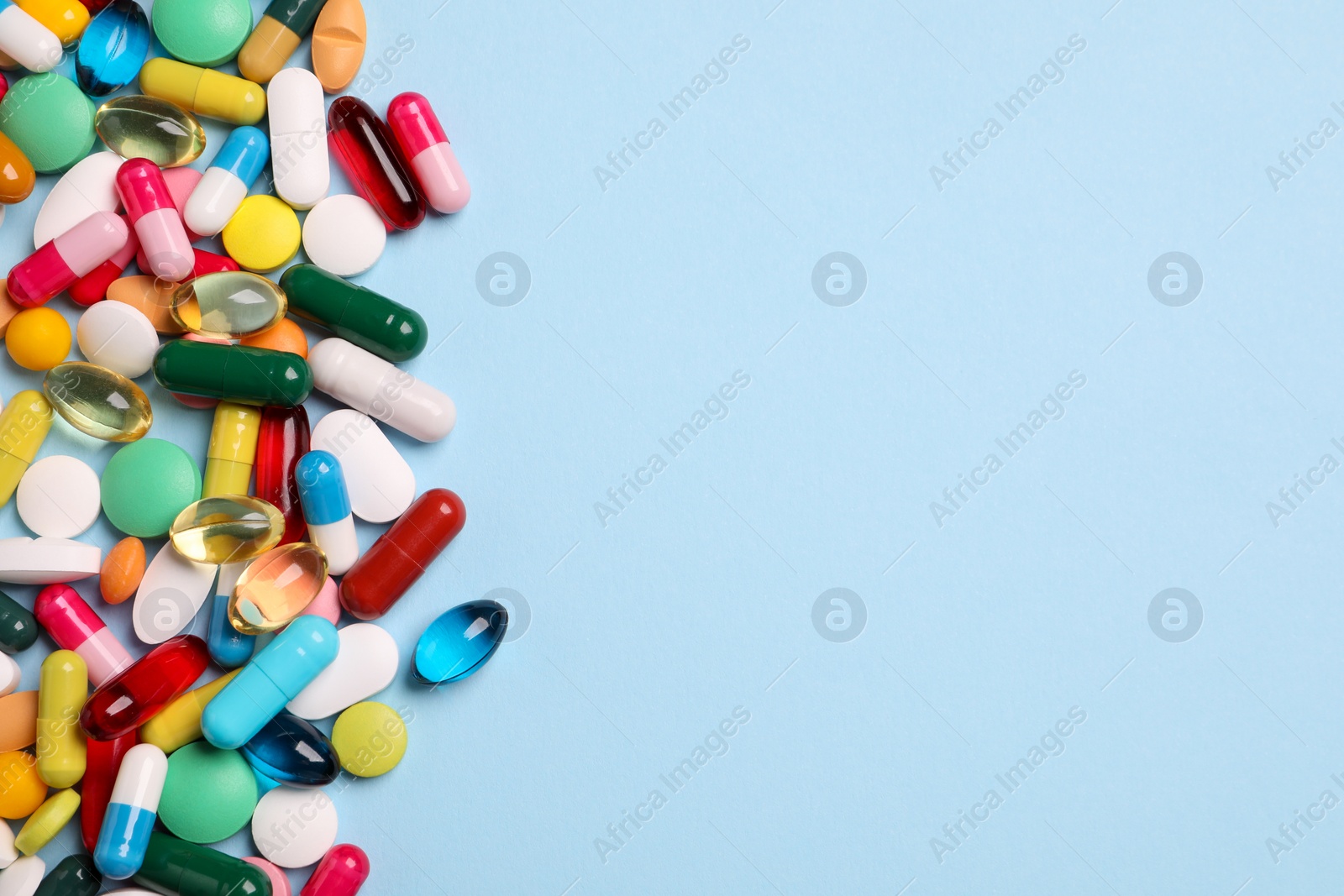 Photo of Many different pills on light blue background, flat lay. Space for text