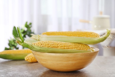 Photo of Bowl with tasty sweet corn cobs on table