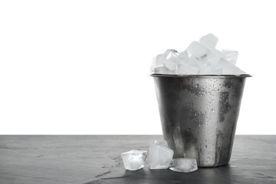 Metal bucket with ice cubes on table against white background