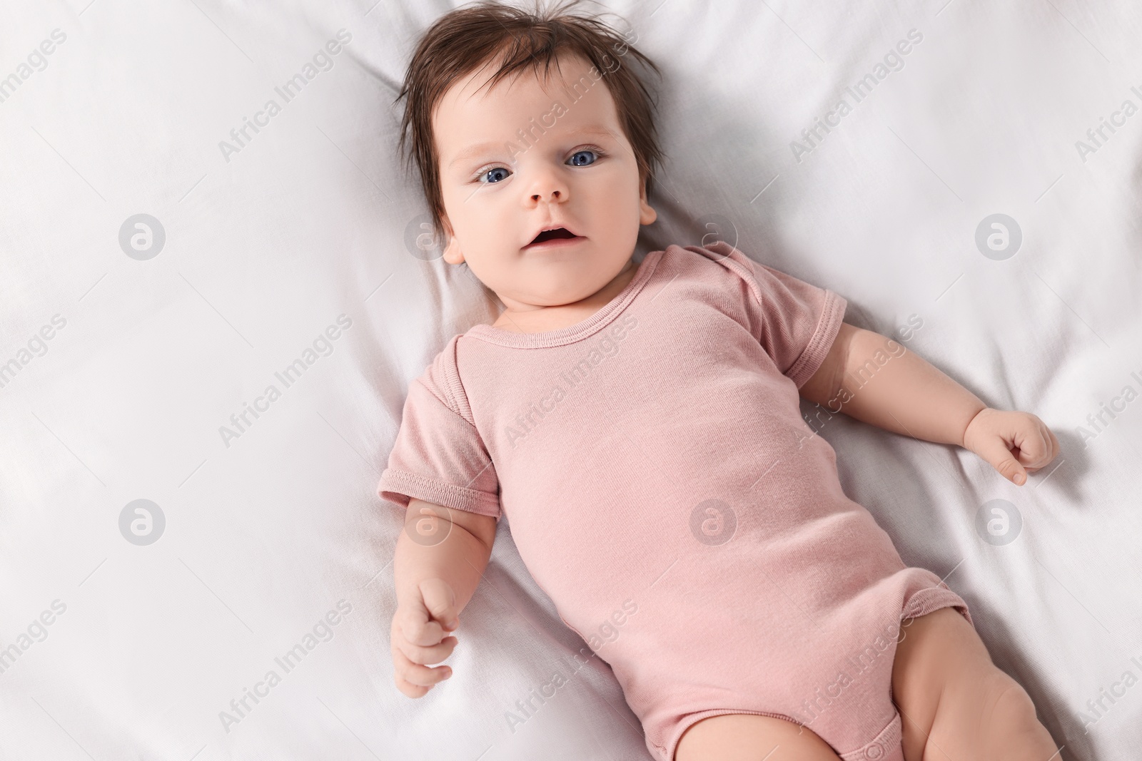 Photo of Cute little baby on cosy bed, top view