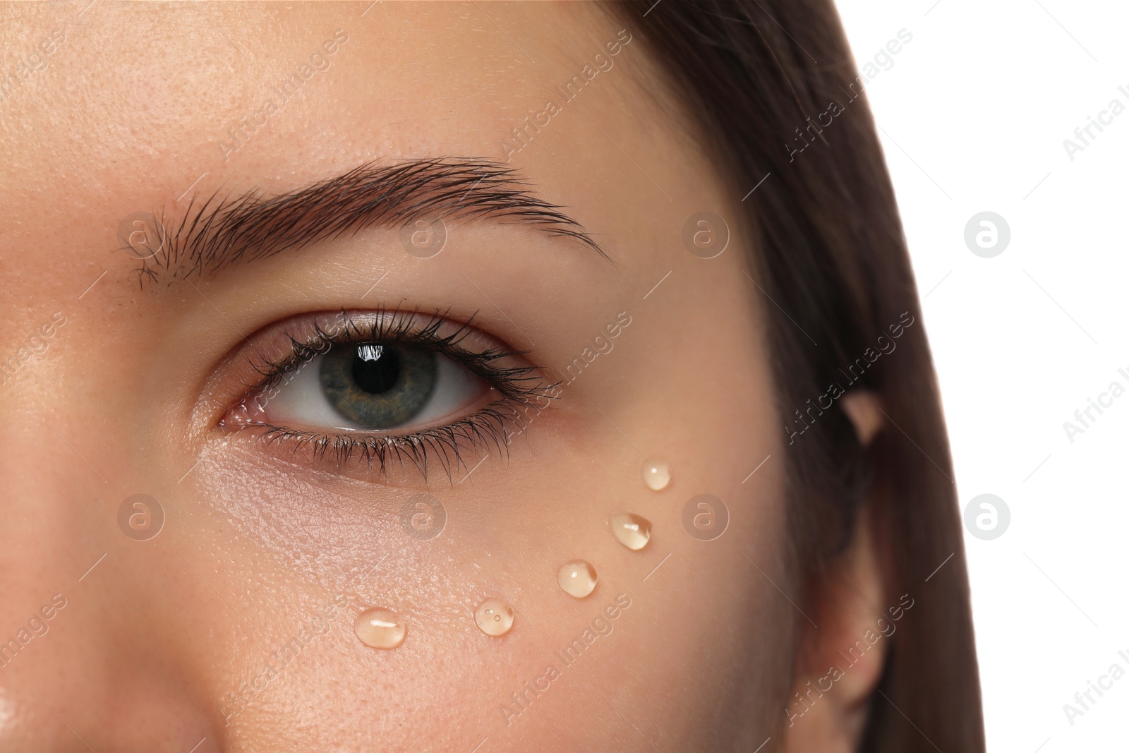 Photo of Young woman with cream around eye on white background, closeup