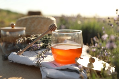 Jar of honey on wooden table in lavender field