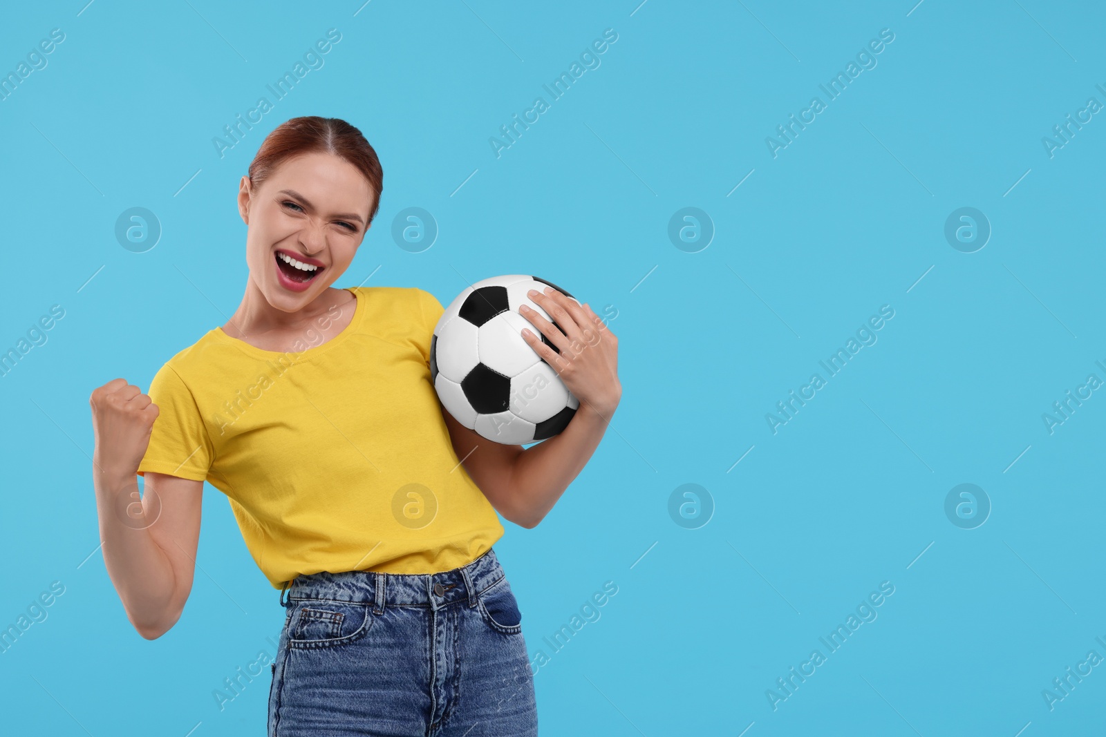 Photo of Emotional fan holding football ball and celebrating on light blue background, space for text