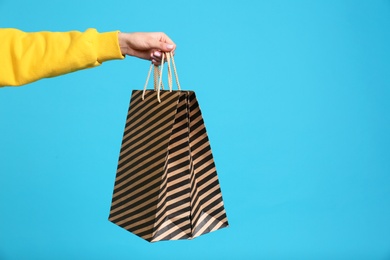 Photo of Young woman holding paper bags on blue background, closeup