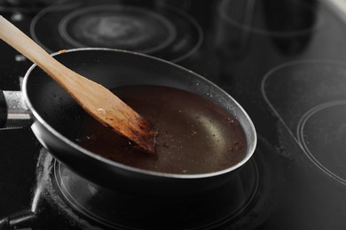 Photo of Frying pan with spatula and used cooking oil on stove