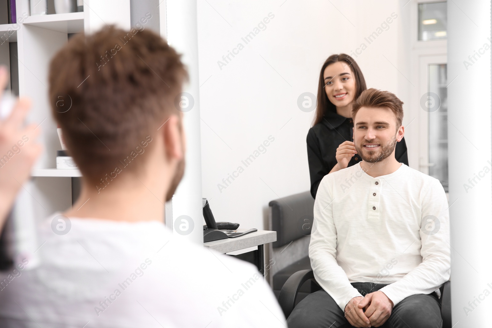 Photo of Professional female hairdresser working with client in salon