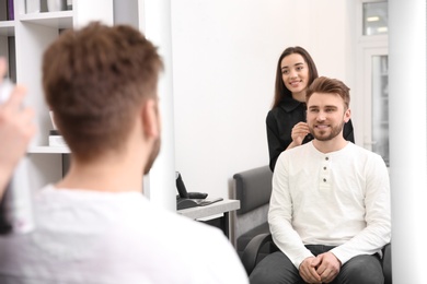 Photo of Professional female hairdresser working with client in salon