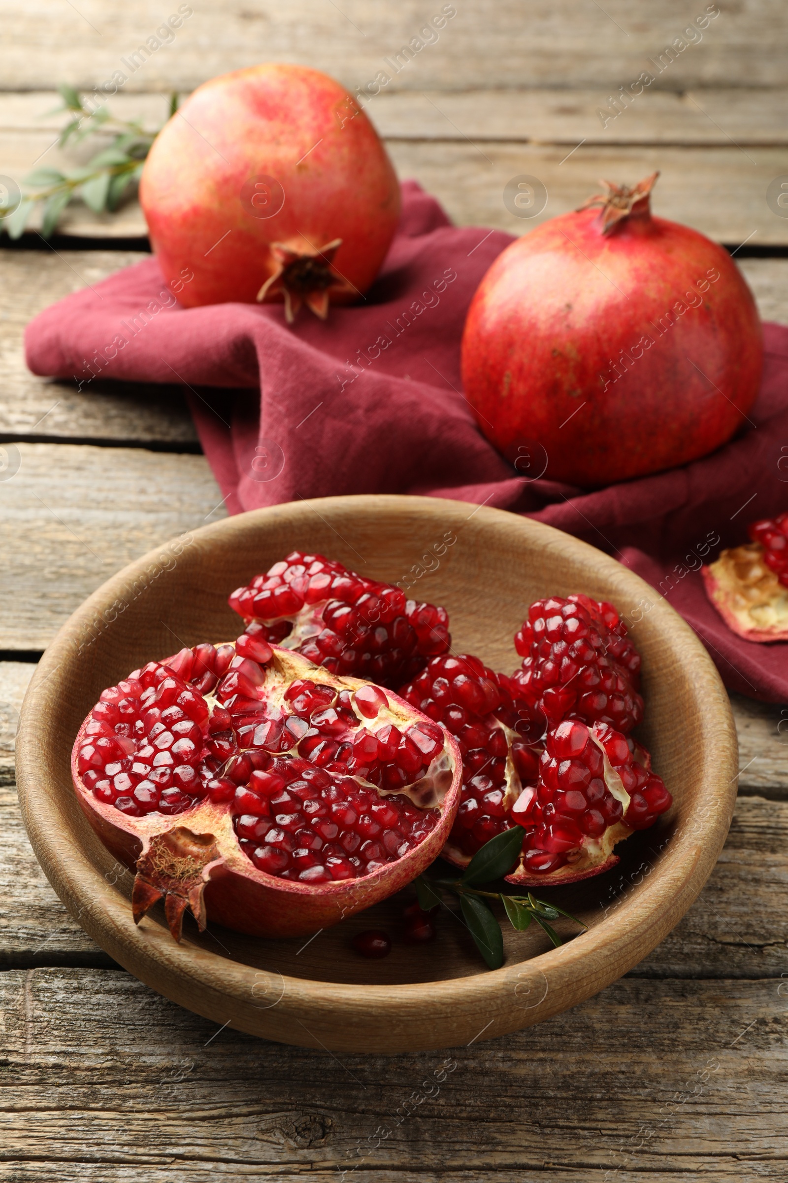 Photo of Fresh pomegranates and green leaves on wooden table