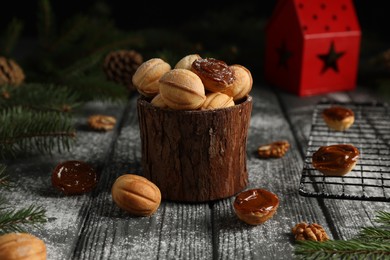 Photo of Homemade walnut shaped cookies with boiled condensed milk, fir branches and cones on wooden table