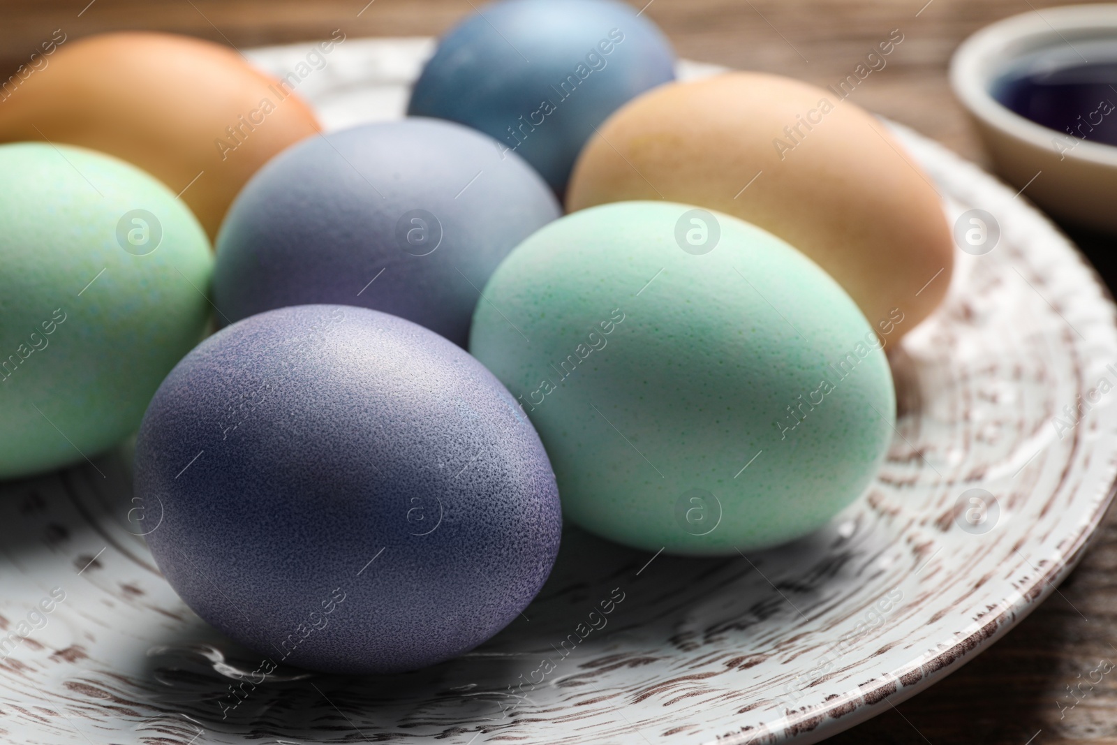 Photo of Easter eggs painted with natural organic dyes on wooden table, closeup