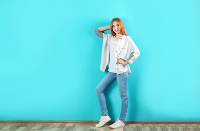 Photo of Young woman in stylish jeans near color wall