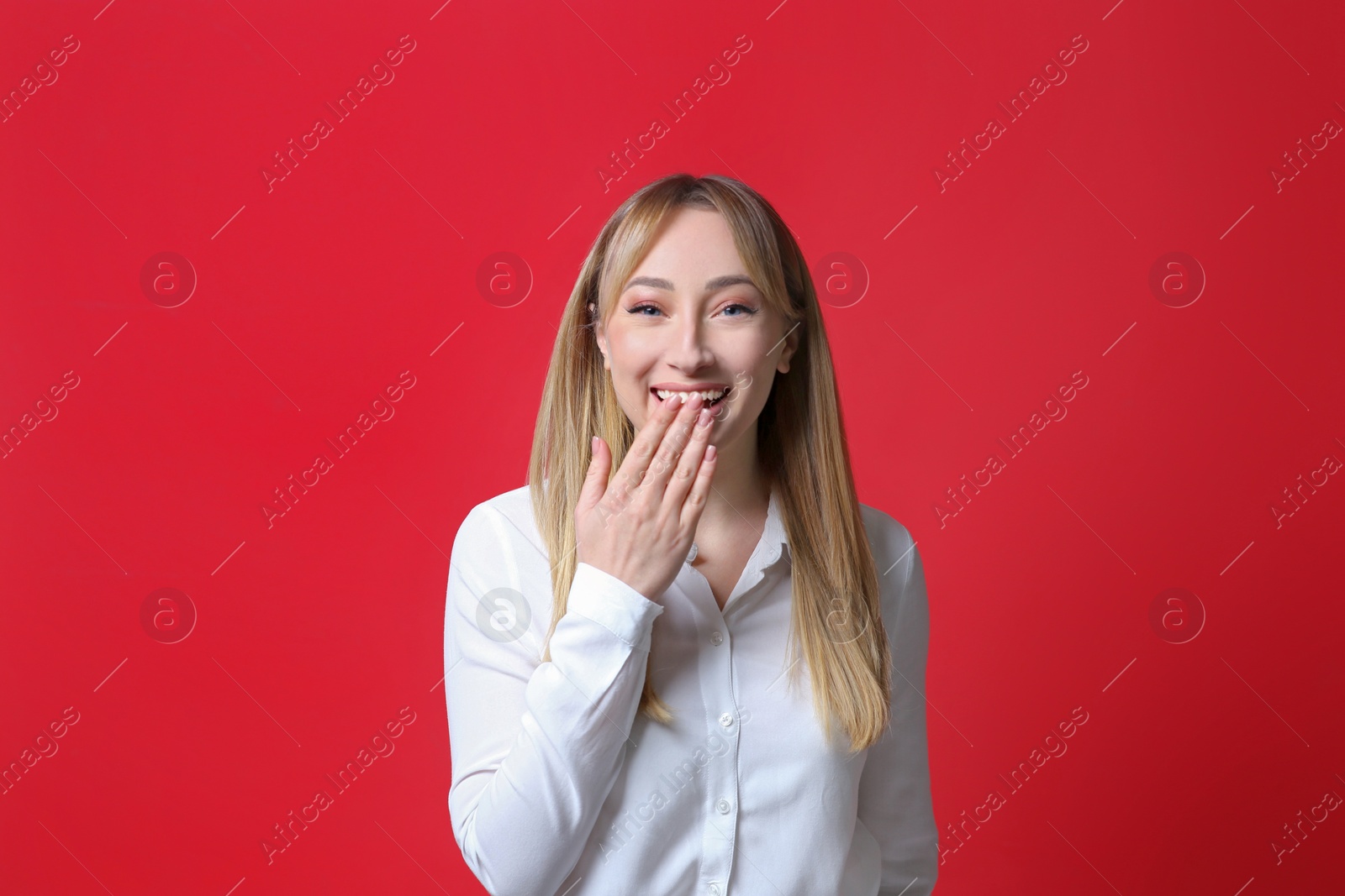 Photo of Beautiful young woman laughing on red background. Funny joke