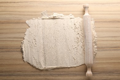 Photo of Flour and rolling pin on wooden table, top view