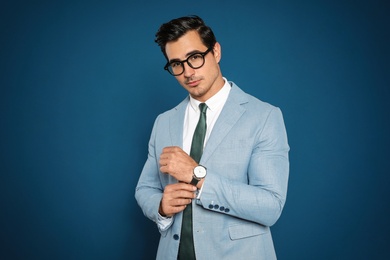 Photo of Portrait of handsome young businessman wearing glasses on blue background