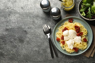 Photo of Delicious spaghetti with burrata cheese and sun dried tomatoes served on grey table, flat lay. Space for text