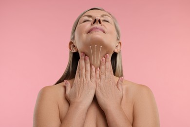 Woman with perfect skin after cosmetic treatment on pink background. Lifting arrows on her neck