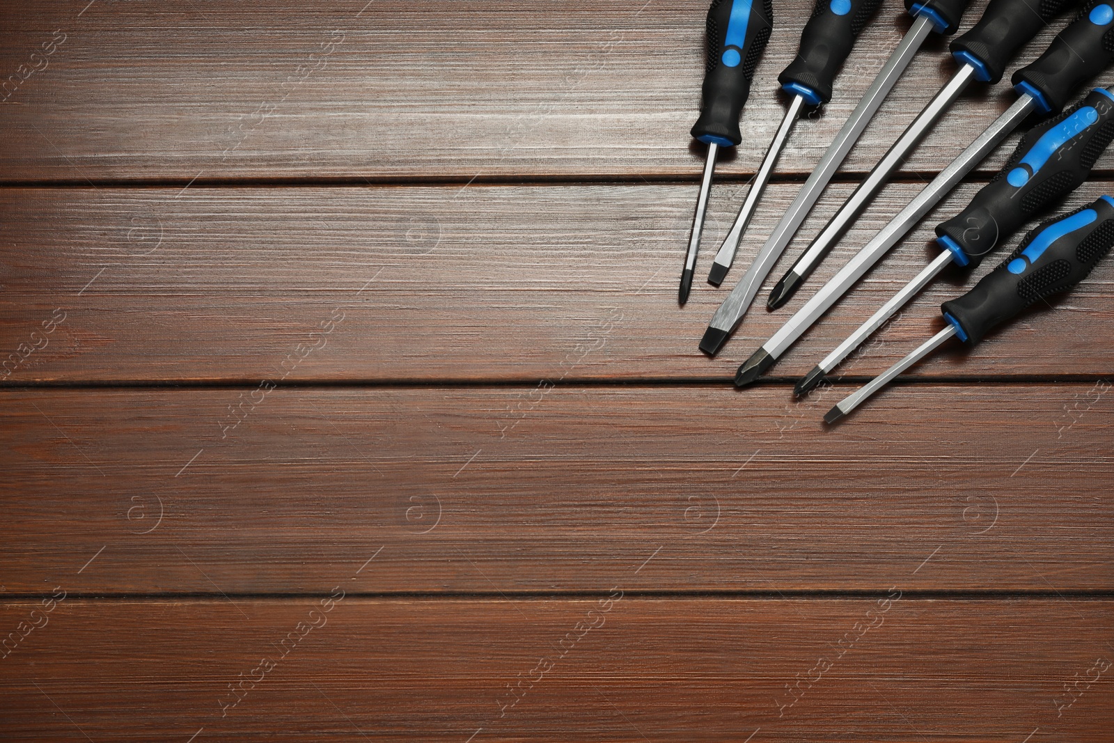 Photo of Set of screwdrivers on wooden table, top view. Space for text