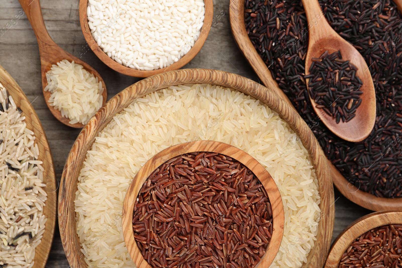 Photo of Different sorts of rice on wooden table, flat lay