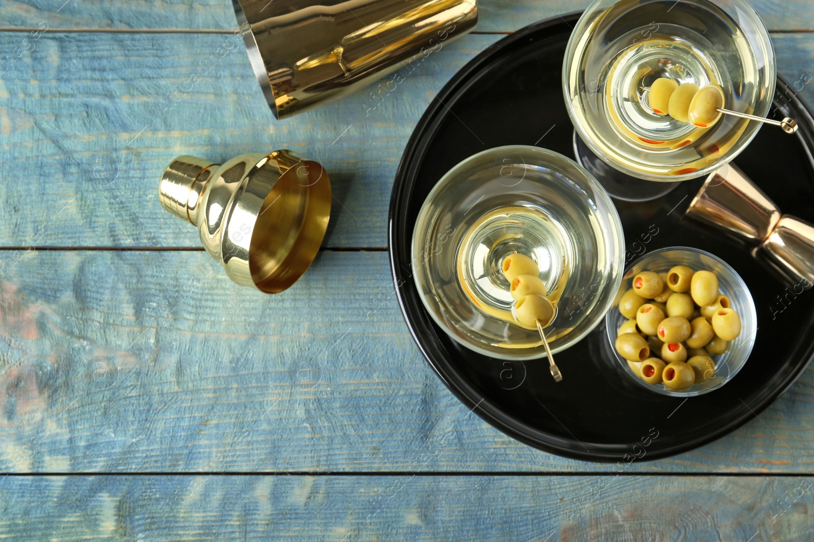 Photo of Glasses of Classic Dry Martini with olives on light blue wooden table, flat lay