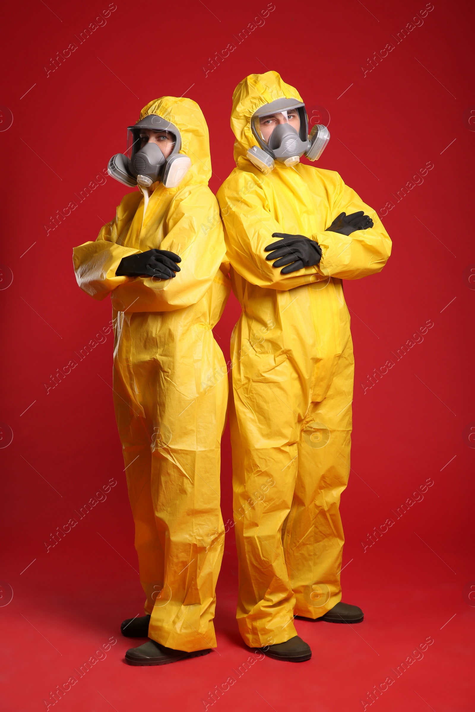 Photo of Man and woman wearing chemical protective suits on red background. Virus research